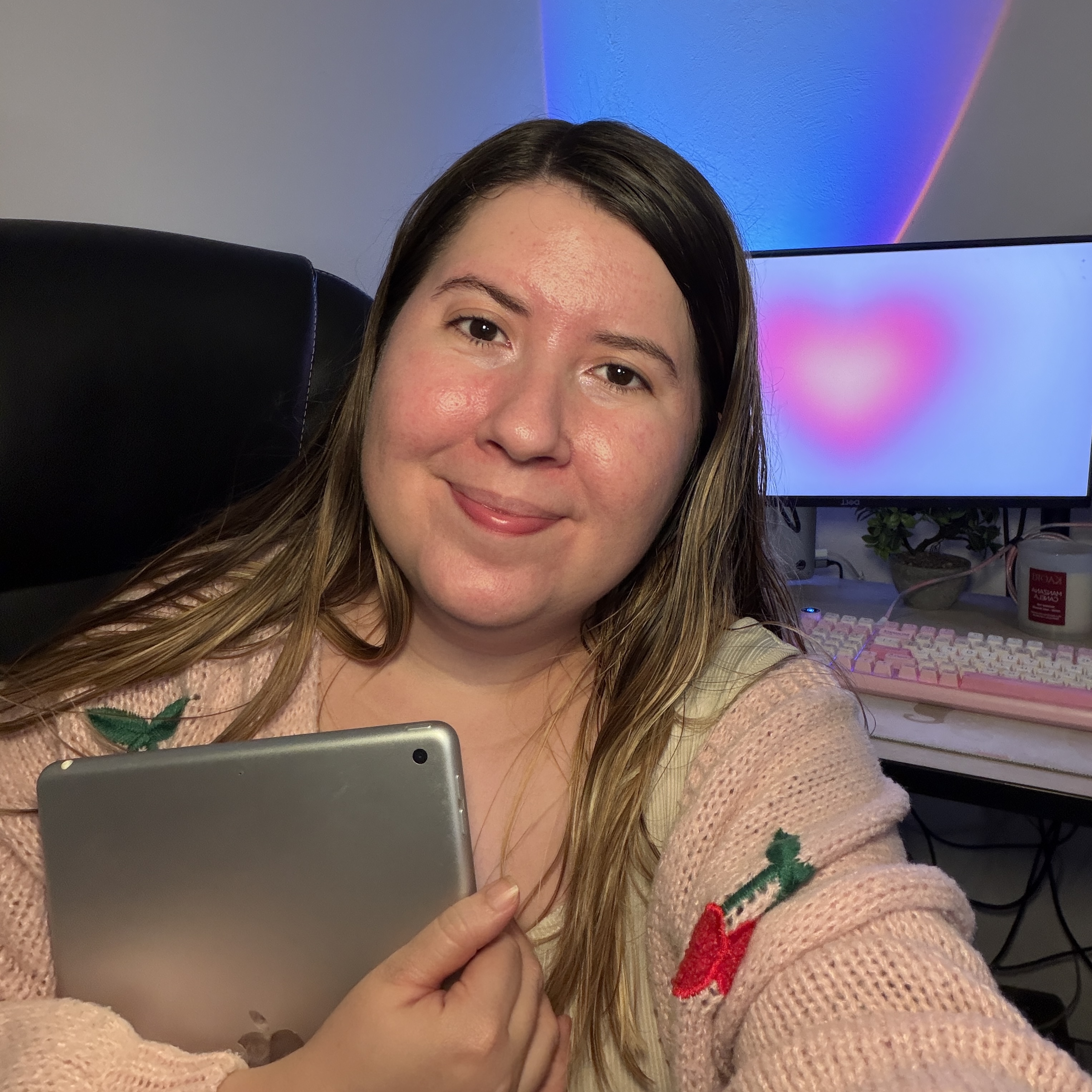 Gaby sonriendo en su escritorio con una tablet y un monitor en tonos violetas